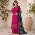 Woman in a pink embroidered outfit with a green dupatta standing indoors with plants in the background

