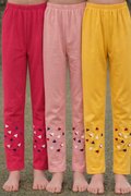 Three pairs of colorful pants with decorative patterns on a grassy background.

